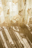 Ruffled linen curtains gently billowing in a sunlit room with soft shadows.