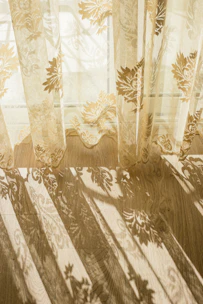 Soft ruffled linen curtains gently swaying by a sunlit window, casting delicate shadows.