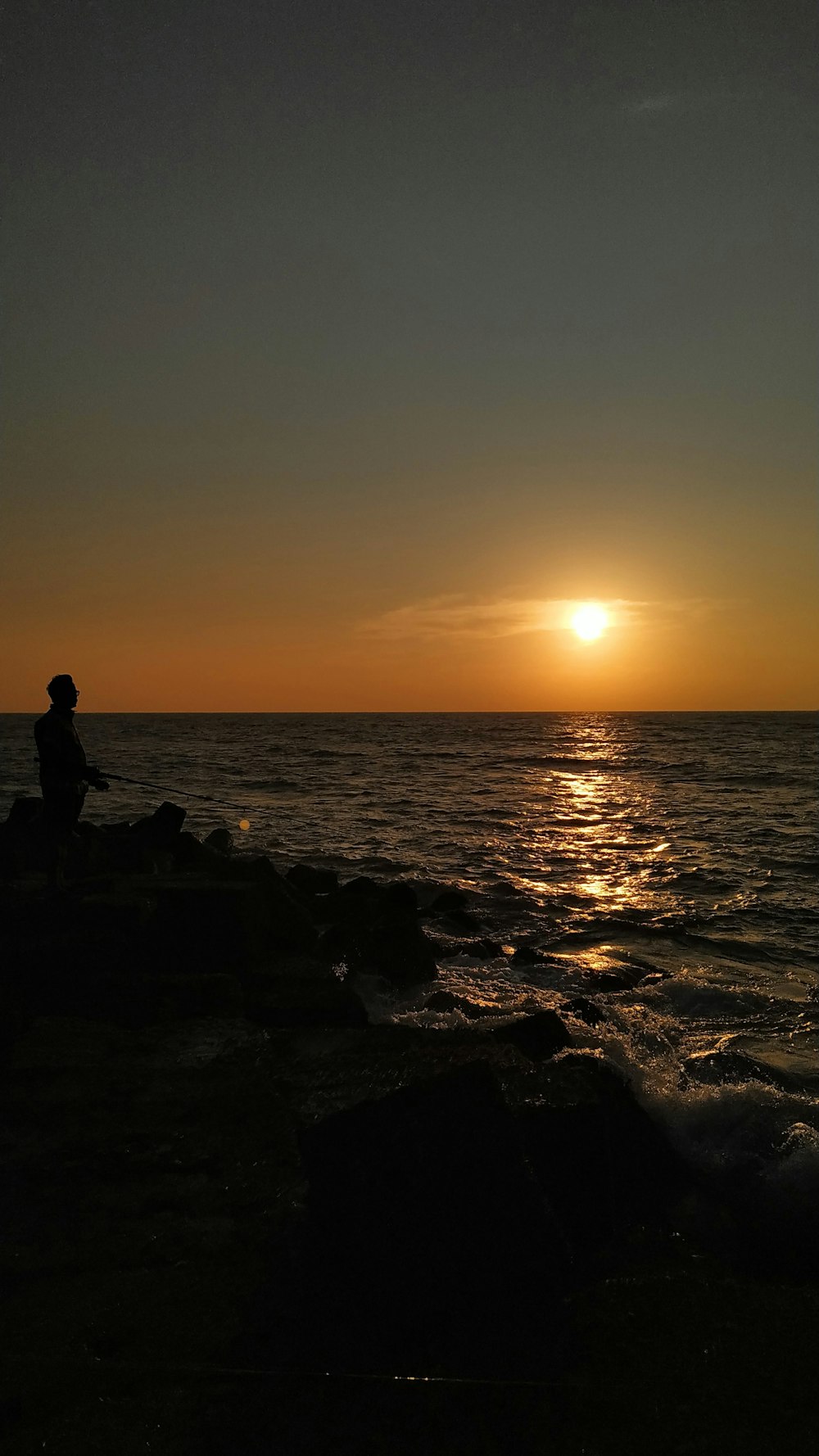 a person sitting on a rock watching the sun set