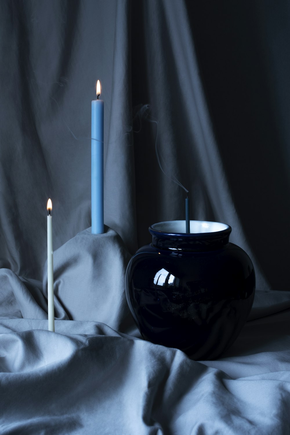 a candle is lit next to a black vase