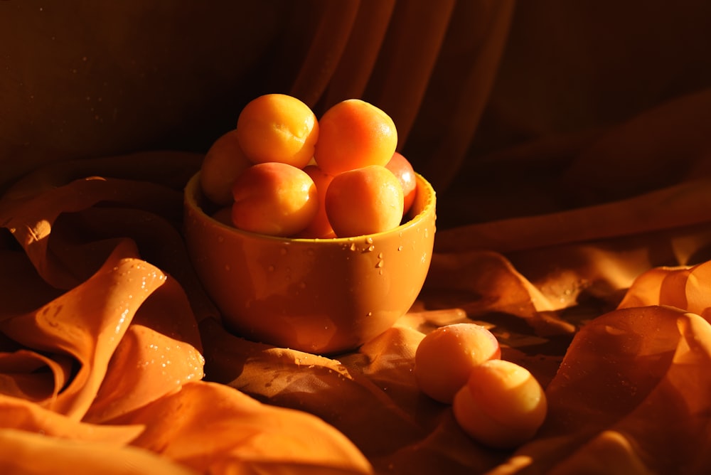 a yellow bowl filled with oranges on top of a bed