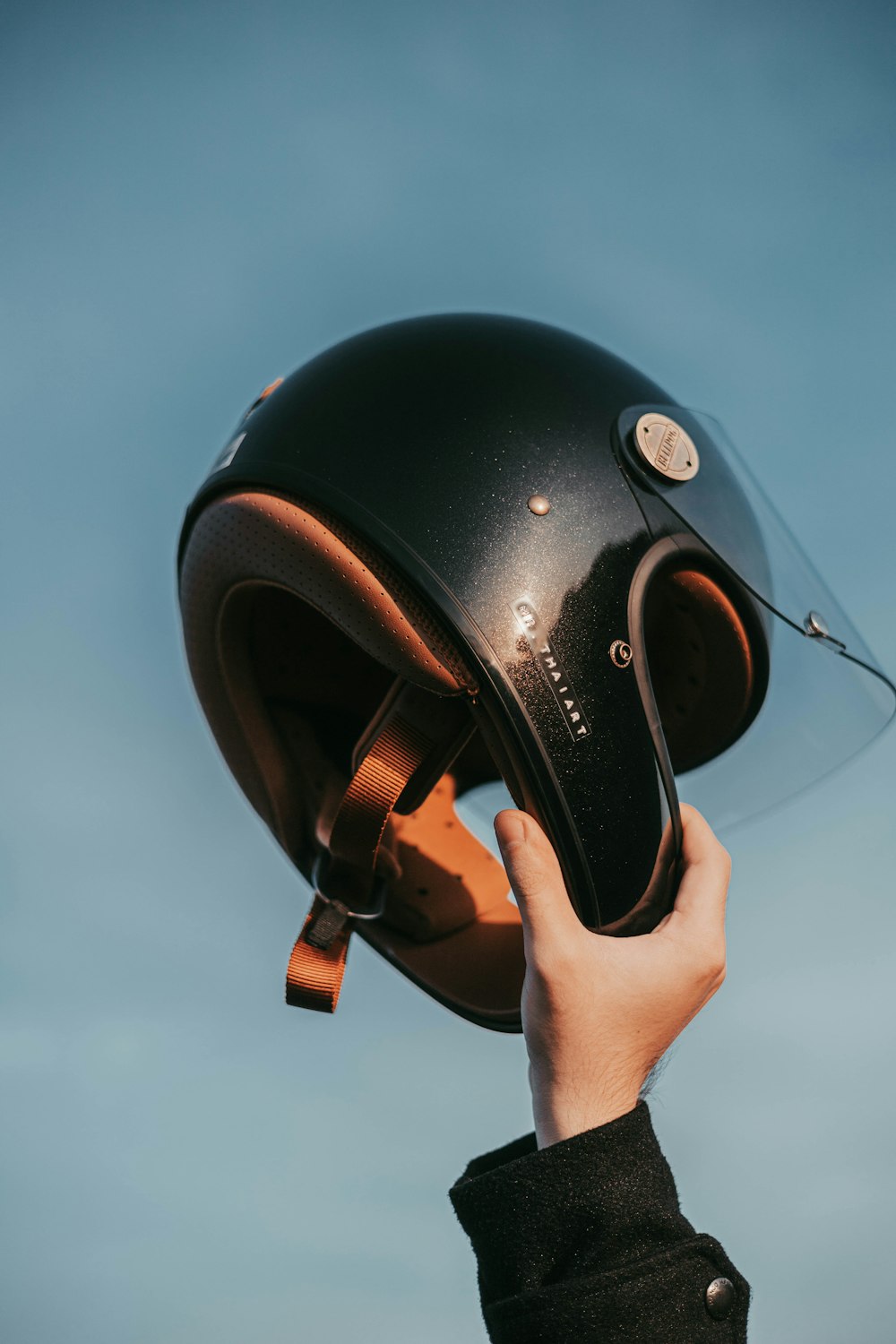Una persona sostiene un casco hacia el cielo