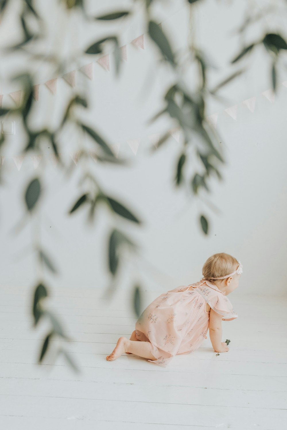 a little girl sitting on the floor in front of a tree