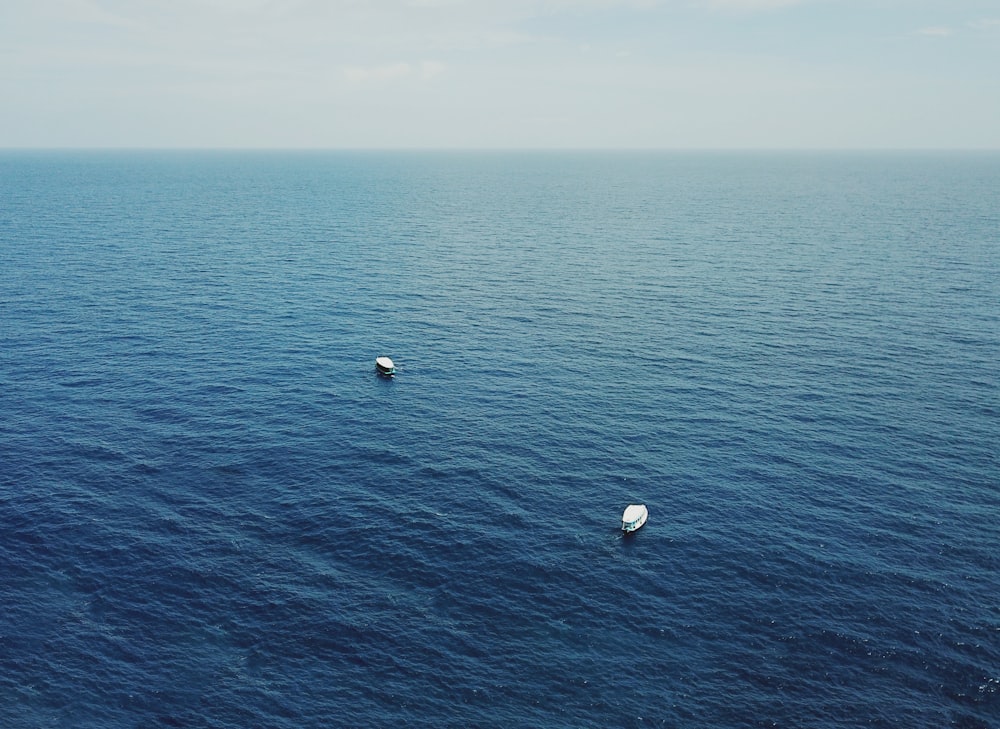 um par de barcos flutuando em cima de um grande corpo de água