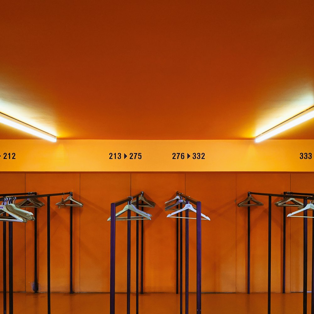 a row of clothes hangers in front of an orange wall