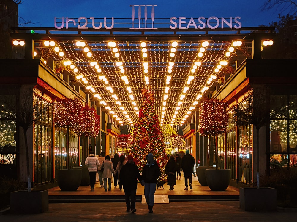 a group of people walking down a street next to a christmas tree