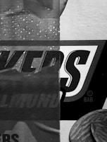 A close-up view of packaging with large, bold text partially visible. The design features a mix of patterns, with dots and textured surfaces. The dominant color scheme is grayscale.