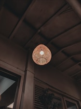 Interior view of Olive & Ember showing rattan lamps casting soft light over olive green walls and wooden tables.