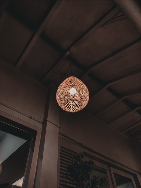 A cozy living room softly illuminated by a warm rattan ceiling light.