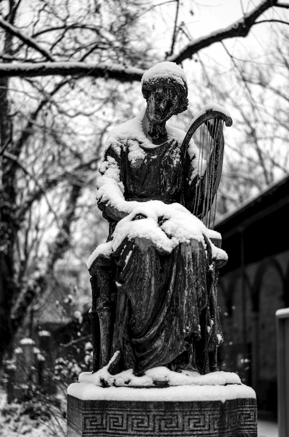 a statue of a woman holding a harp in the snow