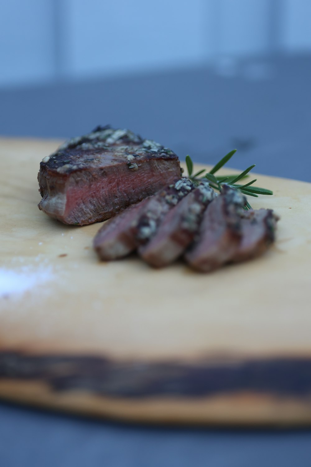 a piece of steak on a cutting board with a sprig of rosemary