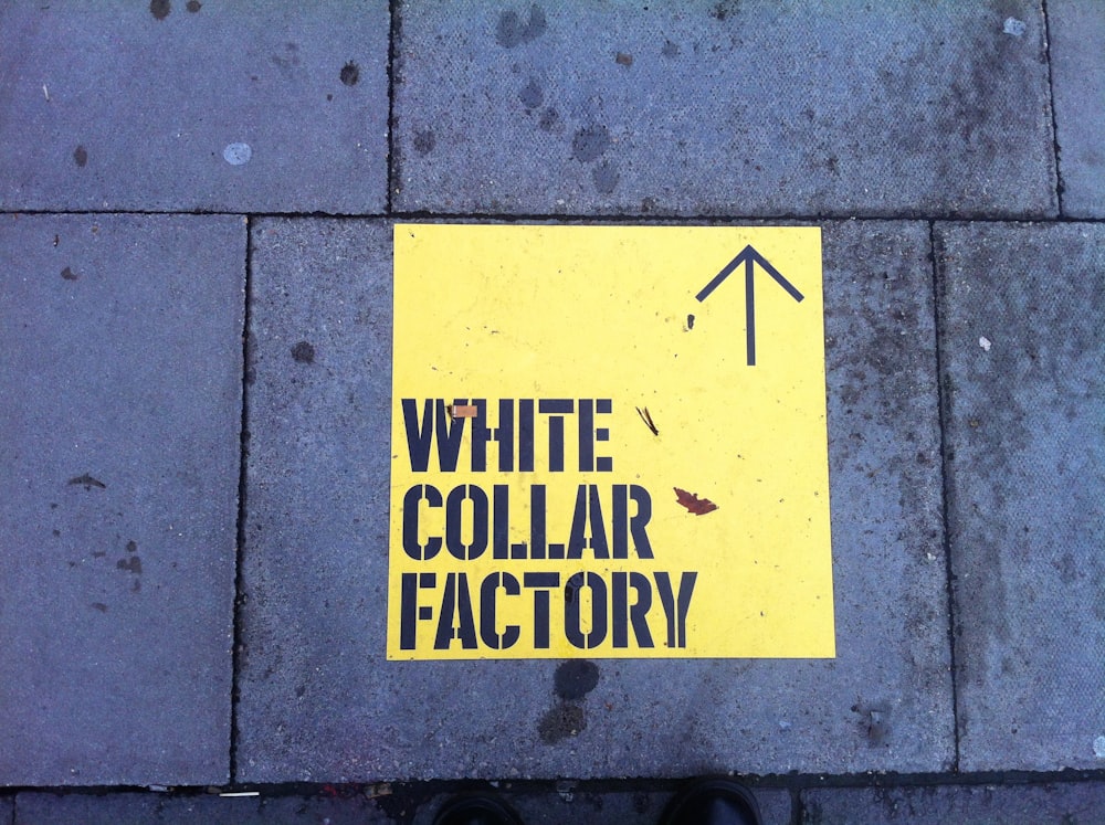 a white collar factory sign on a sidewalk