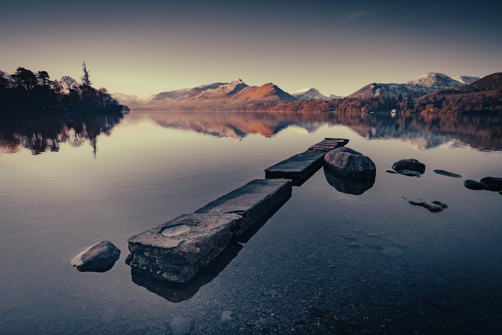 Un lago con rocce e montagne sullo sfondo