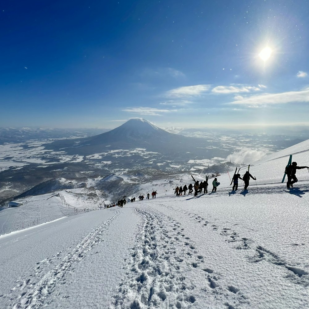 a group of people walking up the side of a snow covered slope