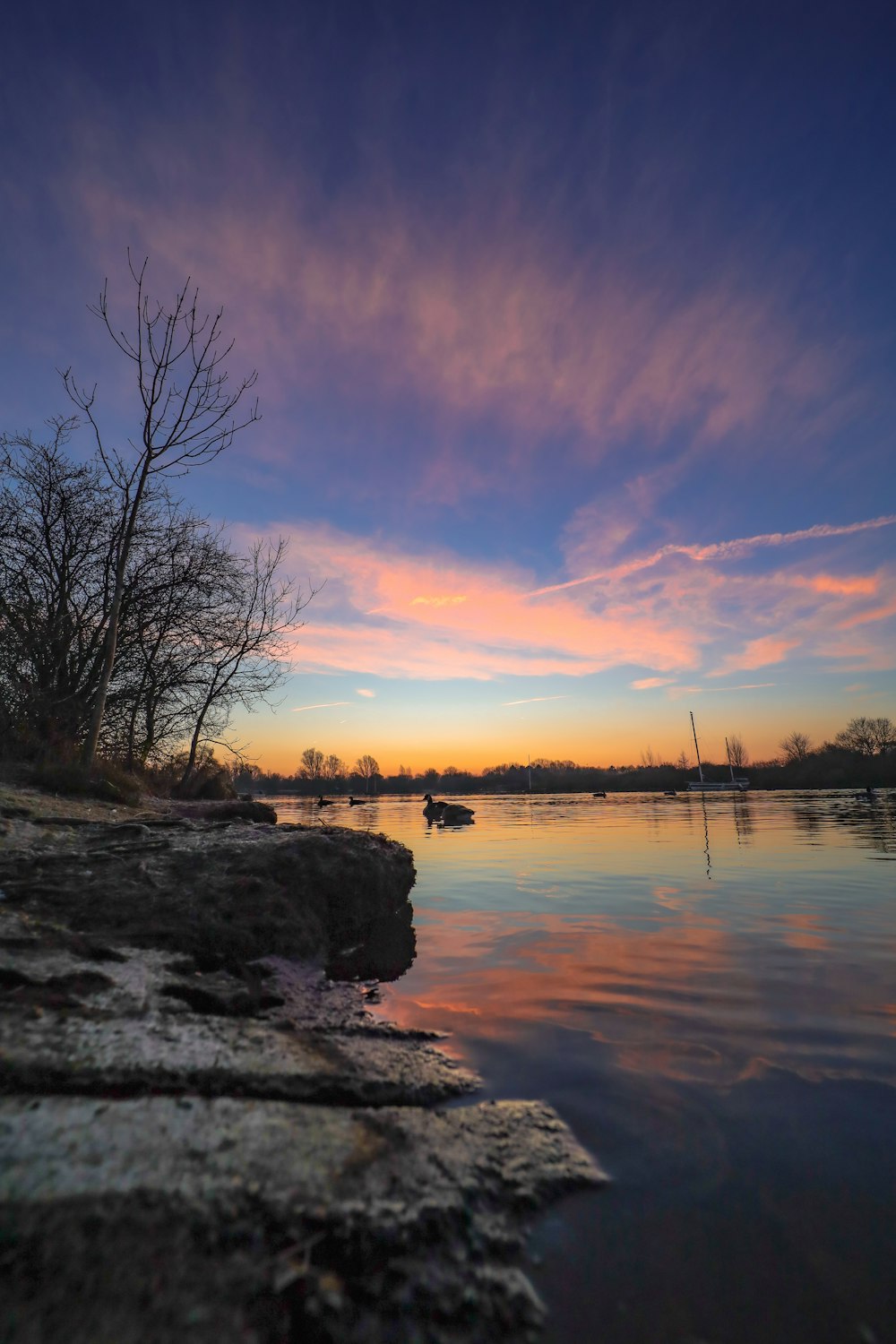 a sunset over a body of water with boats in the distance