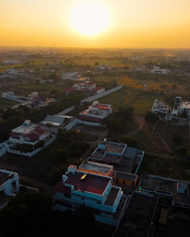 A luxurious aerial view of lush green residential plots with golden sunlight casting warm hues.