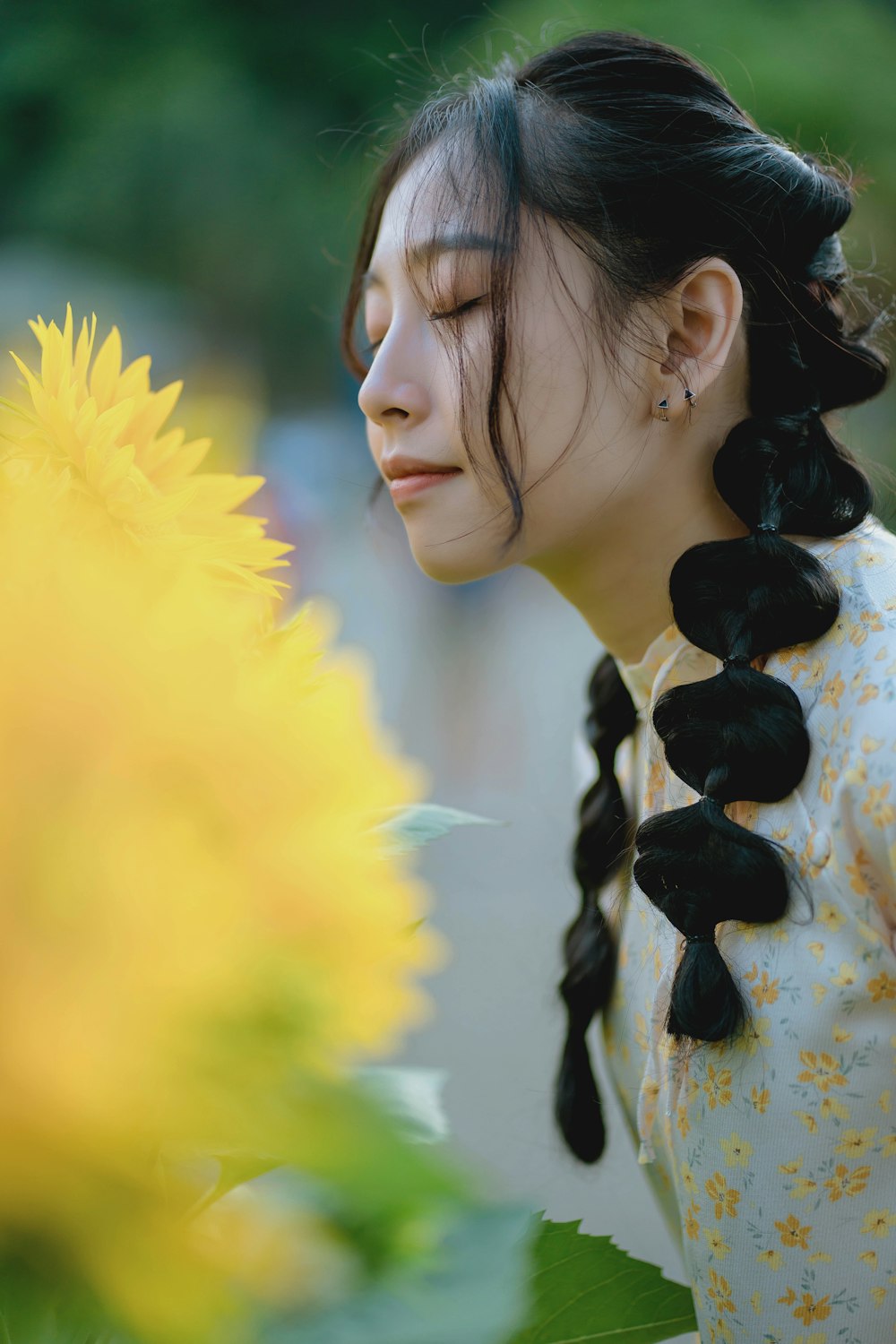 a woman with long black hair standing next to a yellow flower