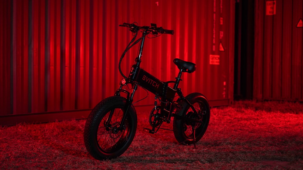 a black bike parked in front of a red wall