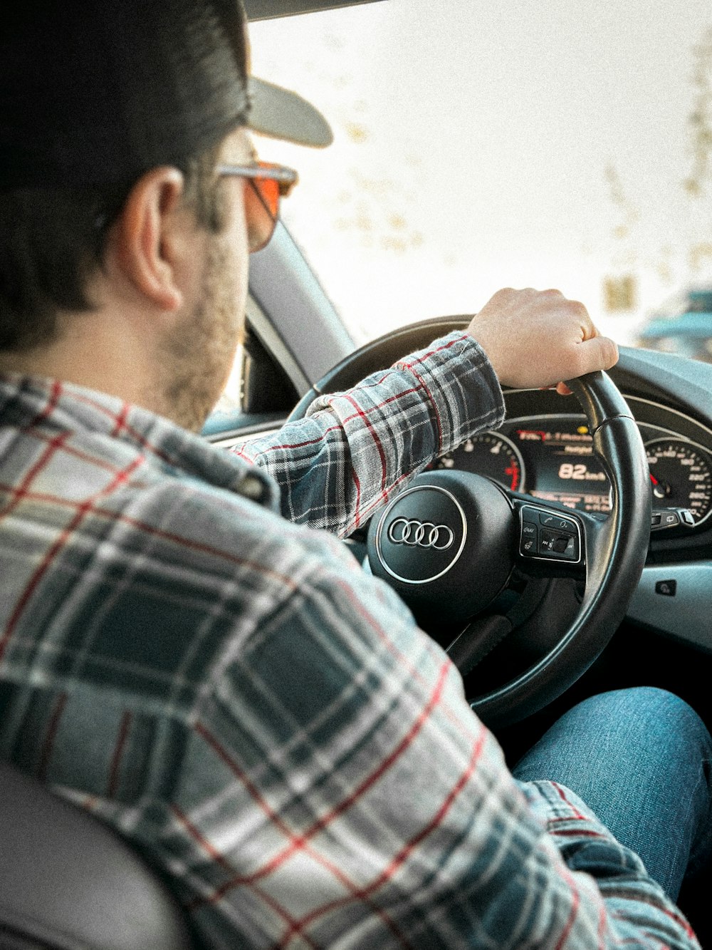 a man in a plaid shirt driving a car