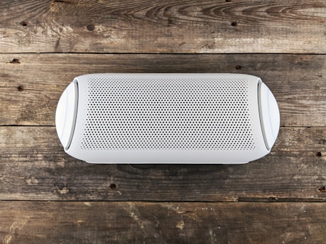 a white speaker sitting on top of a wooden floor