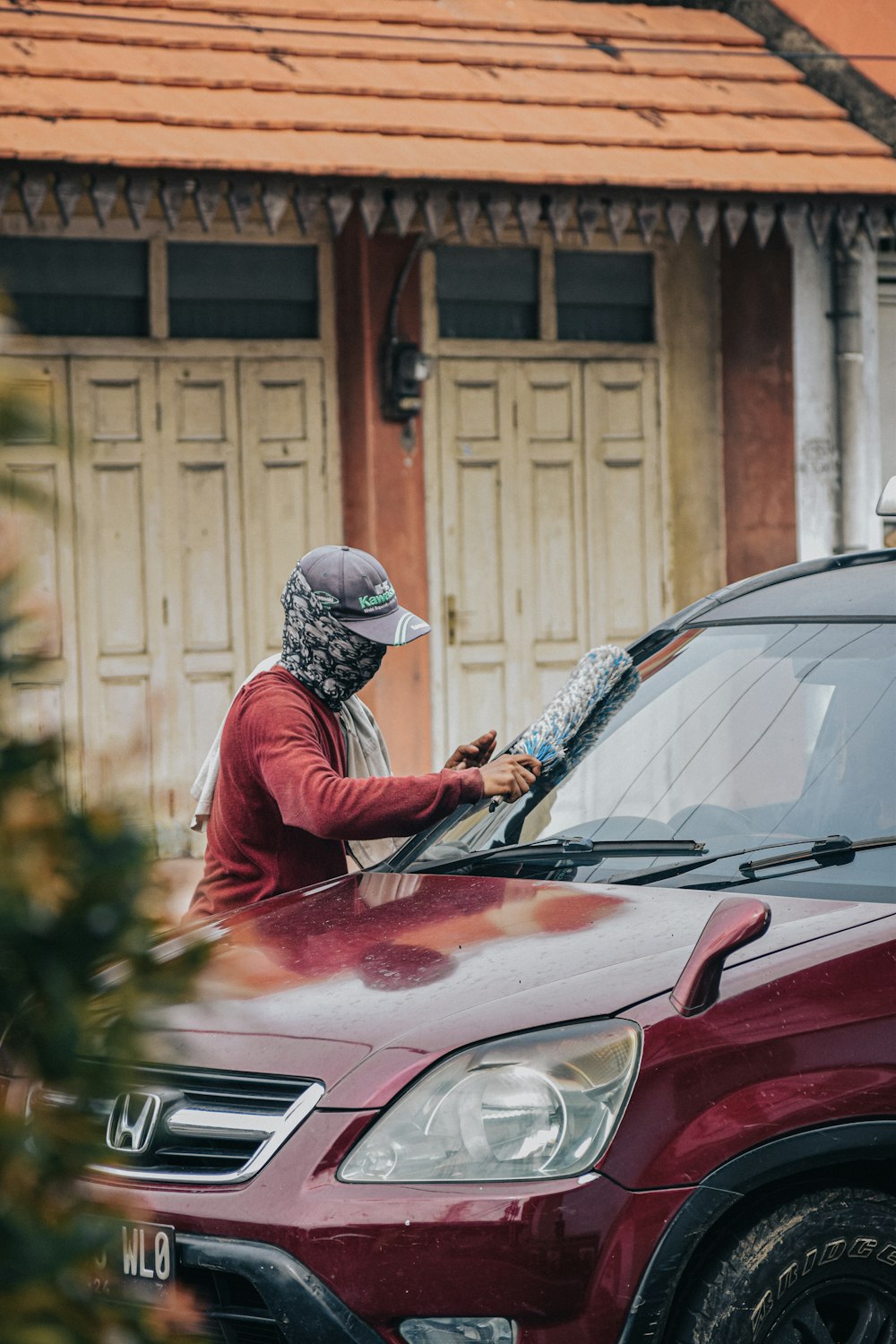 a man in a bandana waxing a car