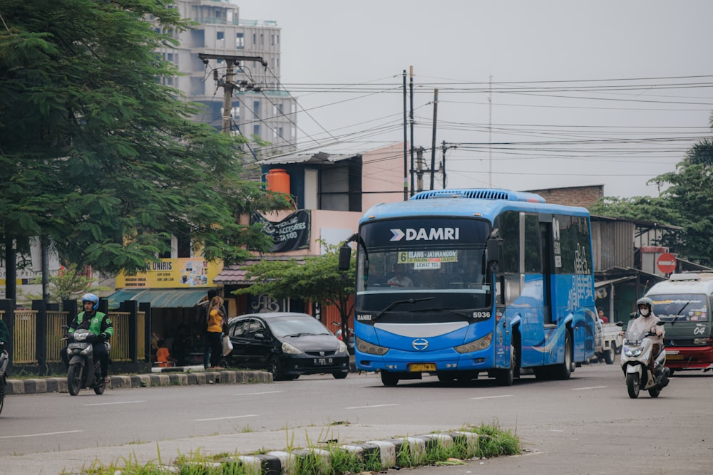 a blue bus driving down a street next to tall buildings