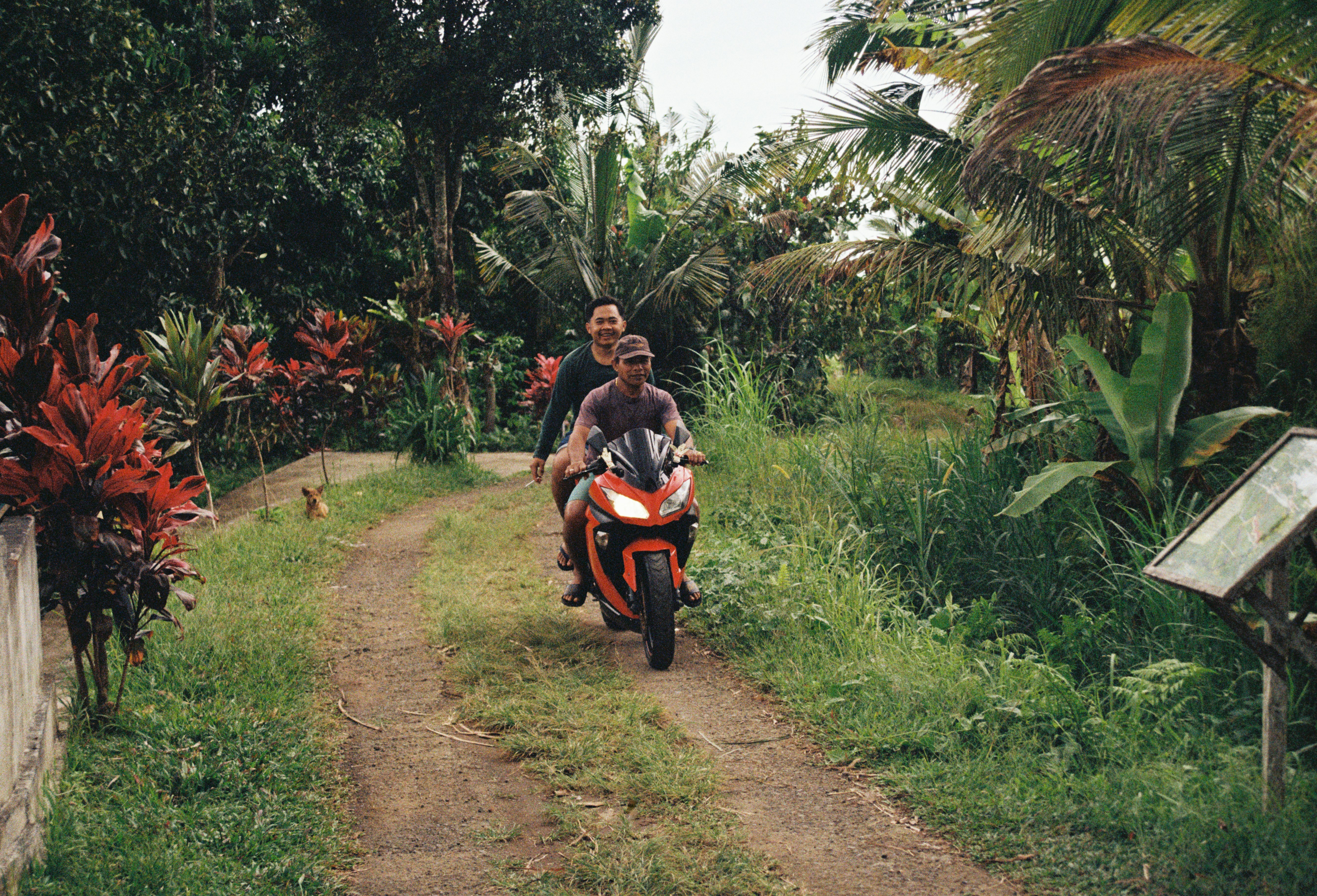 Zwei Personen fahren mit dem Motorrad einen Feldweg hinunter
