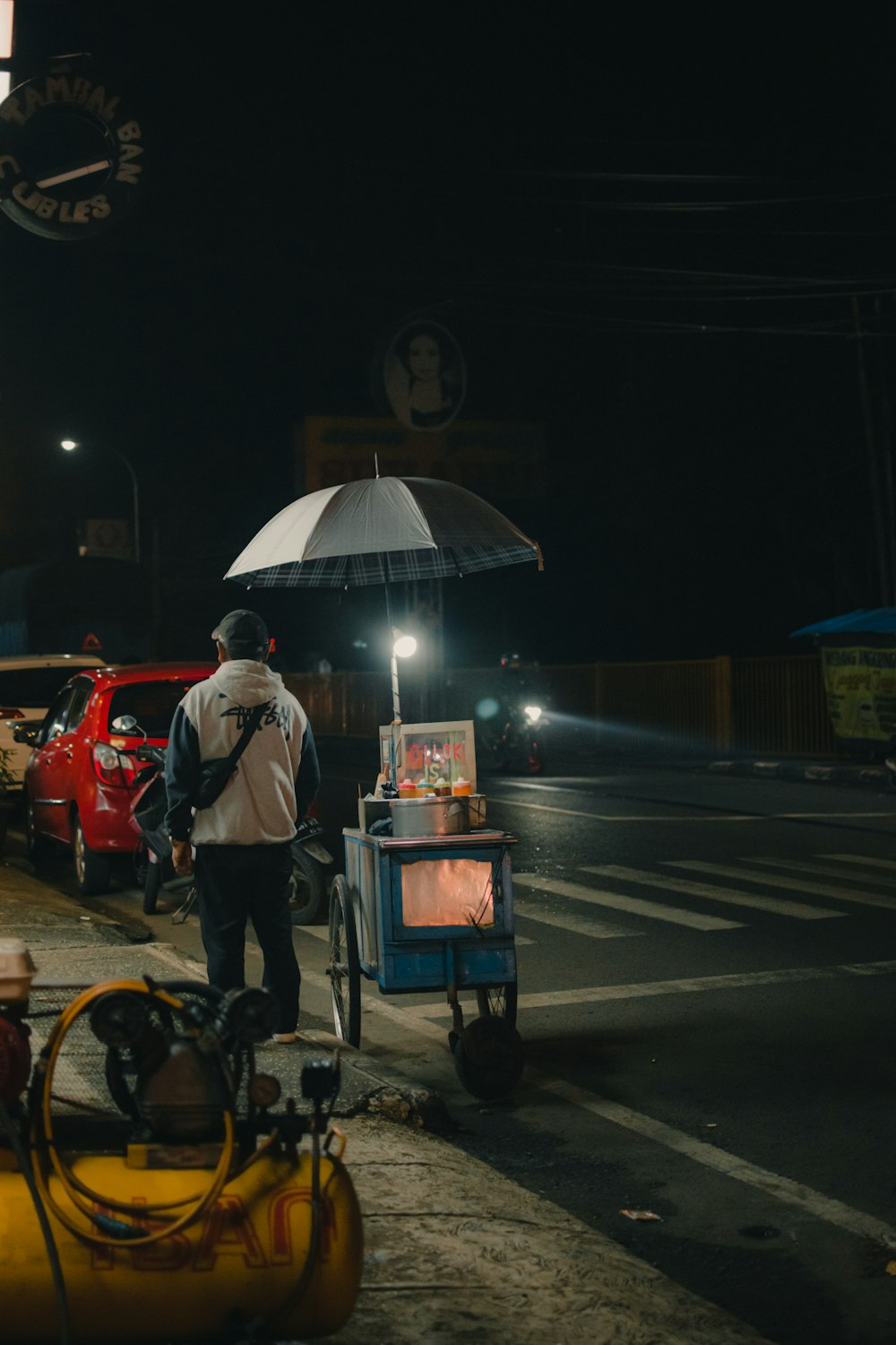 a man with an umbrella standing on the side of the road