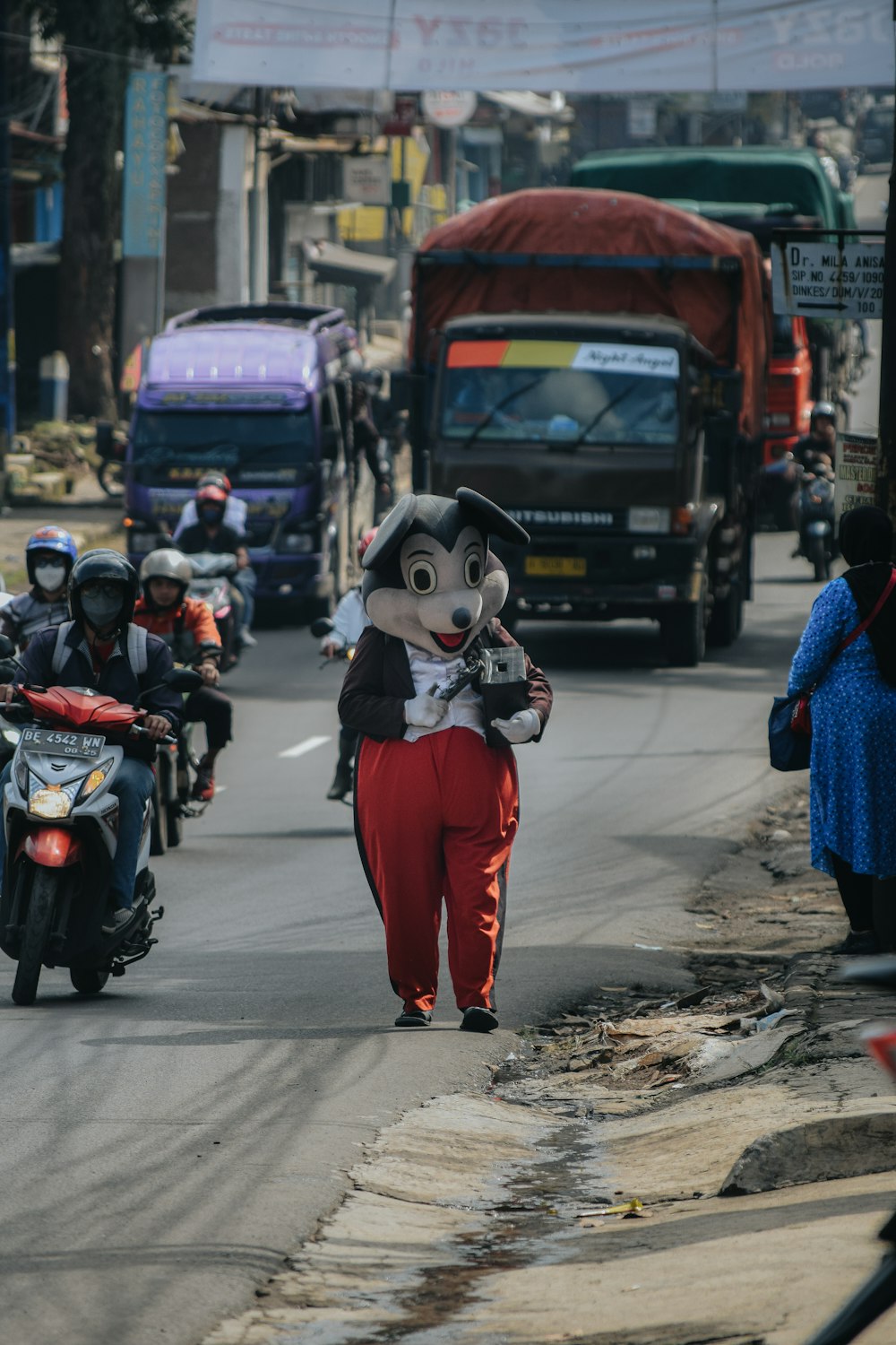 a person in a mouse mask walking down a street