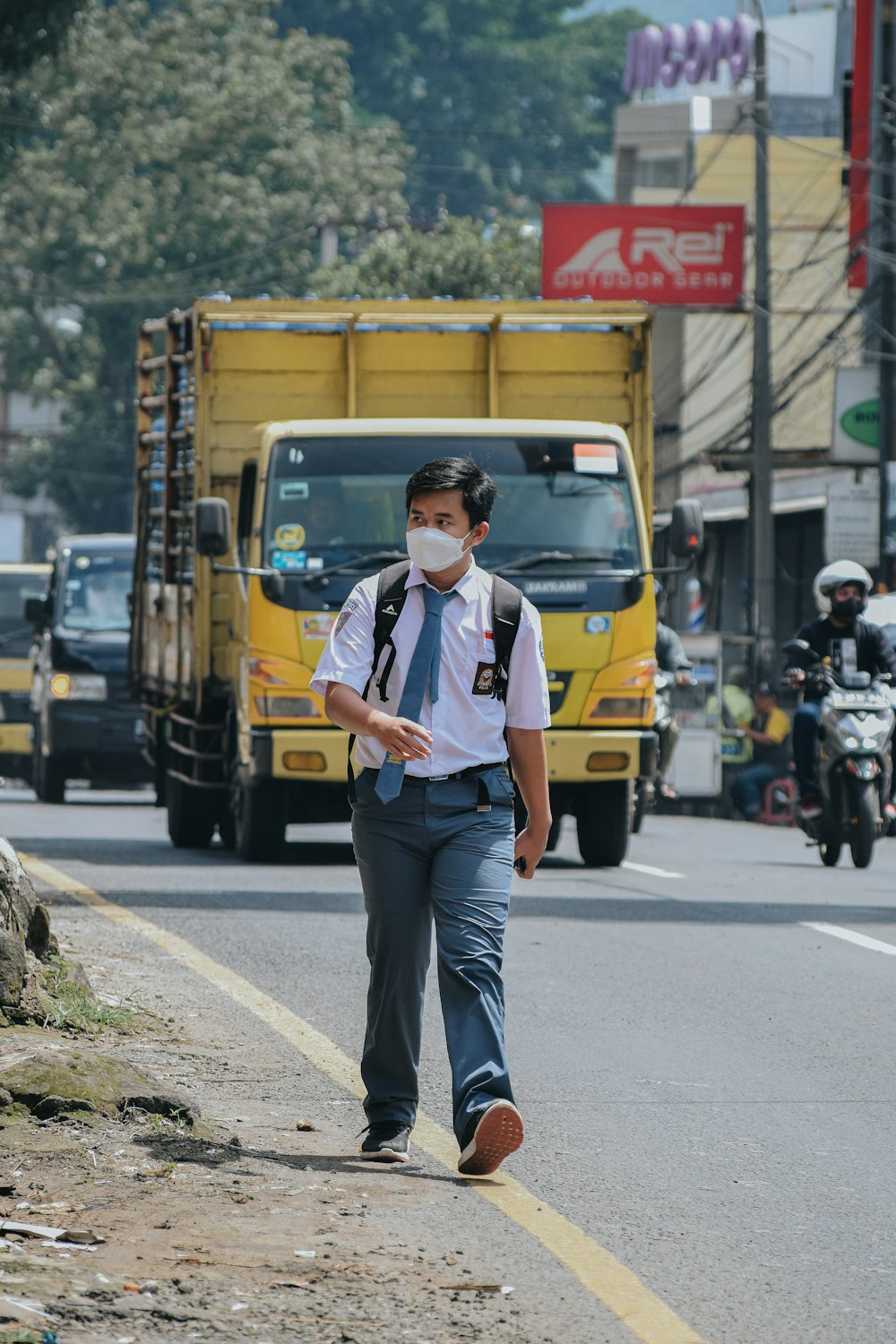 a man wearing a face mask walking down a street