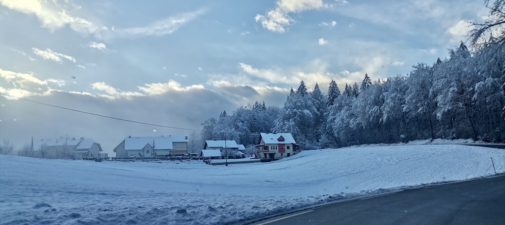 a snow covered road with houses in the distance