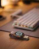 Close-up of a sleek wearable device with emerald green accents on a wooden desk.