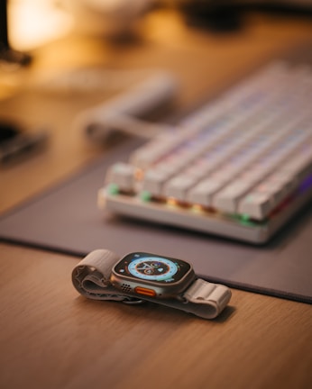 Close-up of a sleek wearable device with emerald green accents on a wooden desk.
