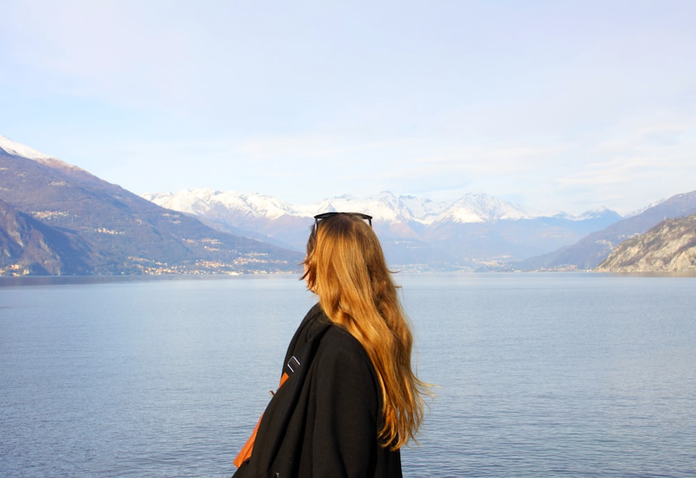 a woman standing on the edge of a cliff overlooking a body of water