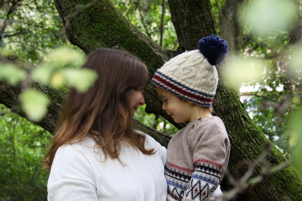 a woman and a child standing next to a tree