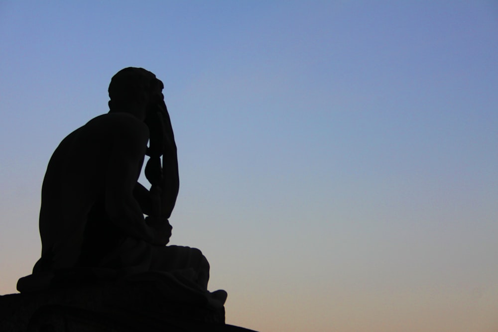 a silhouette of a man sitting on a bench