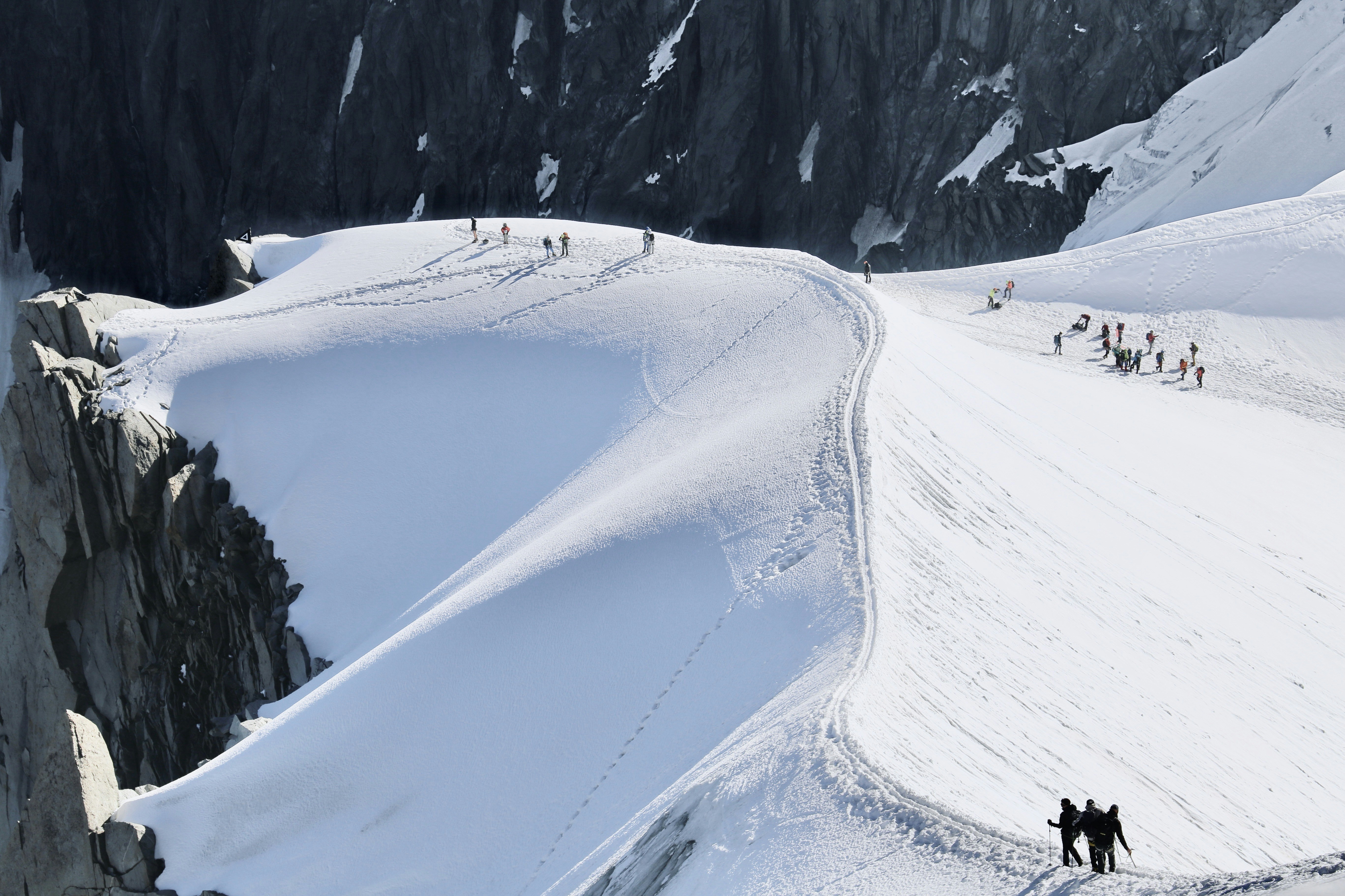 A group of people walking up the side of a snow covered mountain