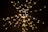 A burst of warm, yellow lights appears against a dark background, resembling sparklers or festively arranged fairy lights. The lights are blurred, giving a sense of motion and a dynamic visual effect.