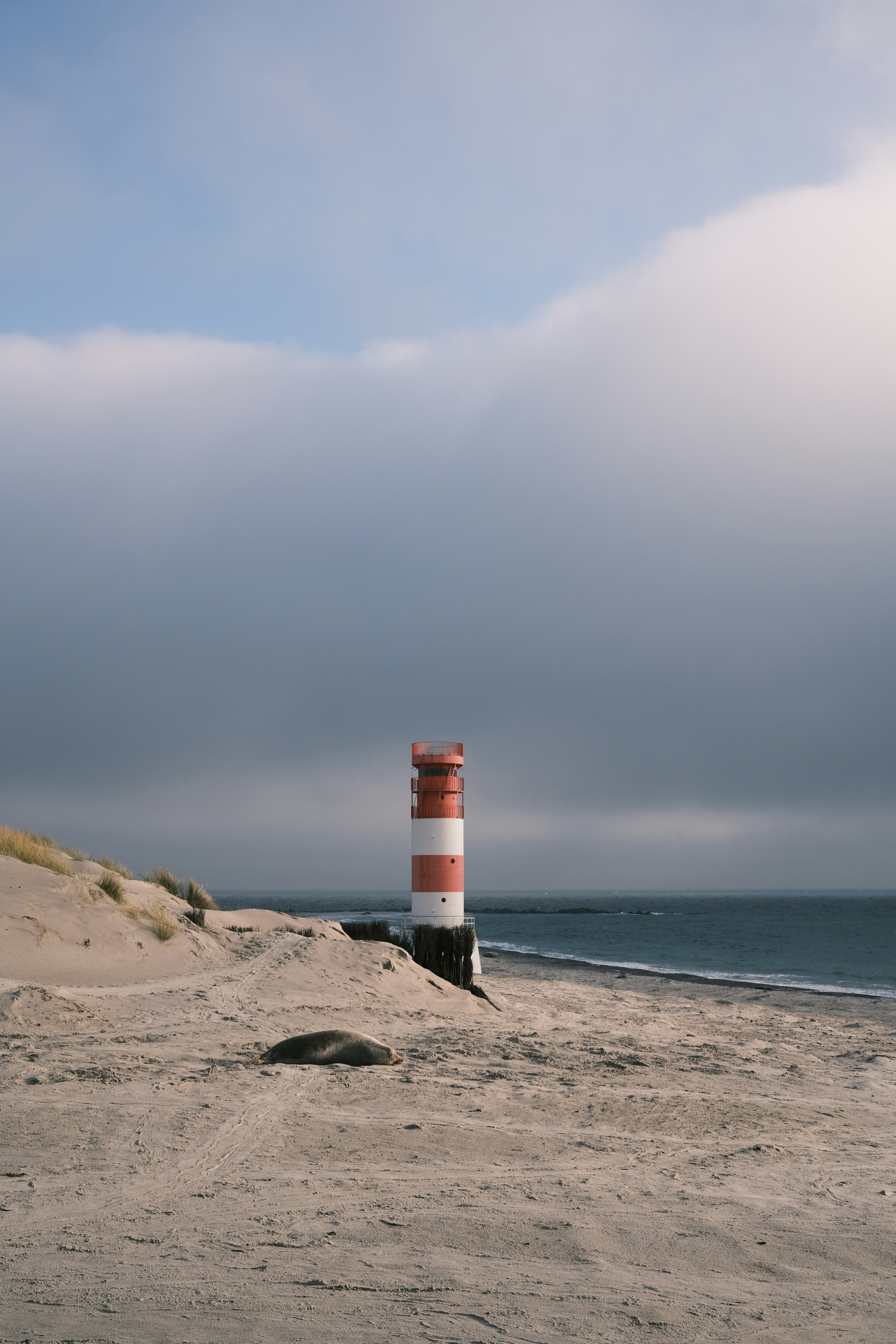 a red and white lighthouse sitting on top of a sandy beach