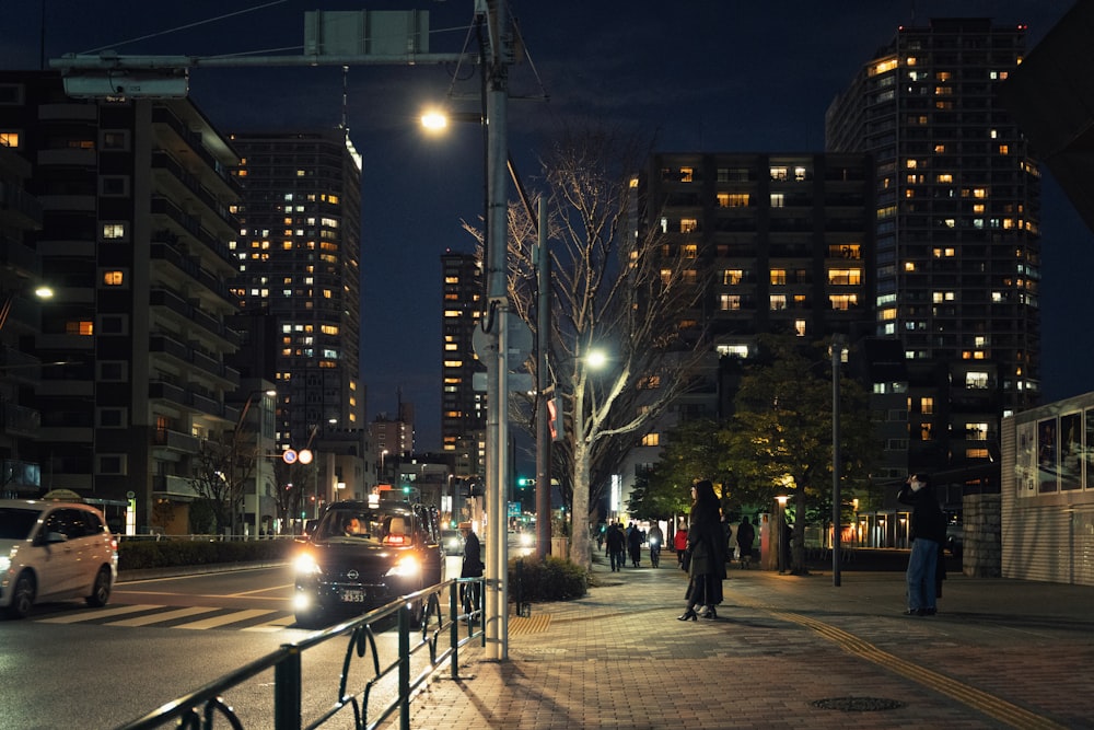 a busy city street at night with cars parked on the side of the road