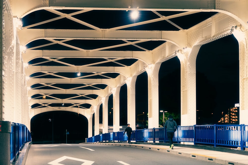 a man walking across a bridge at night