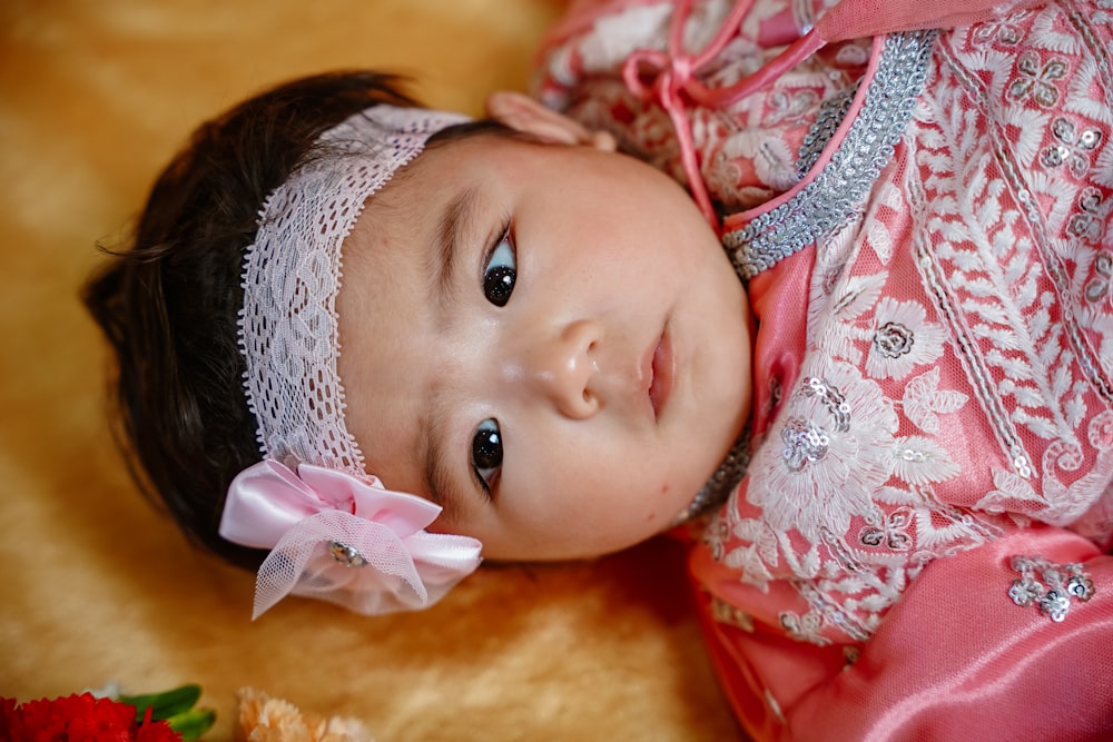 a baby wearing a pink dress and a pink flower