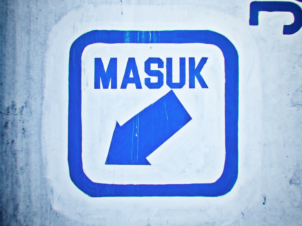 a close up of a blue and white sign with a arrow