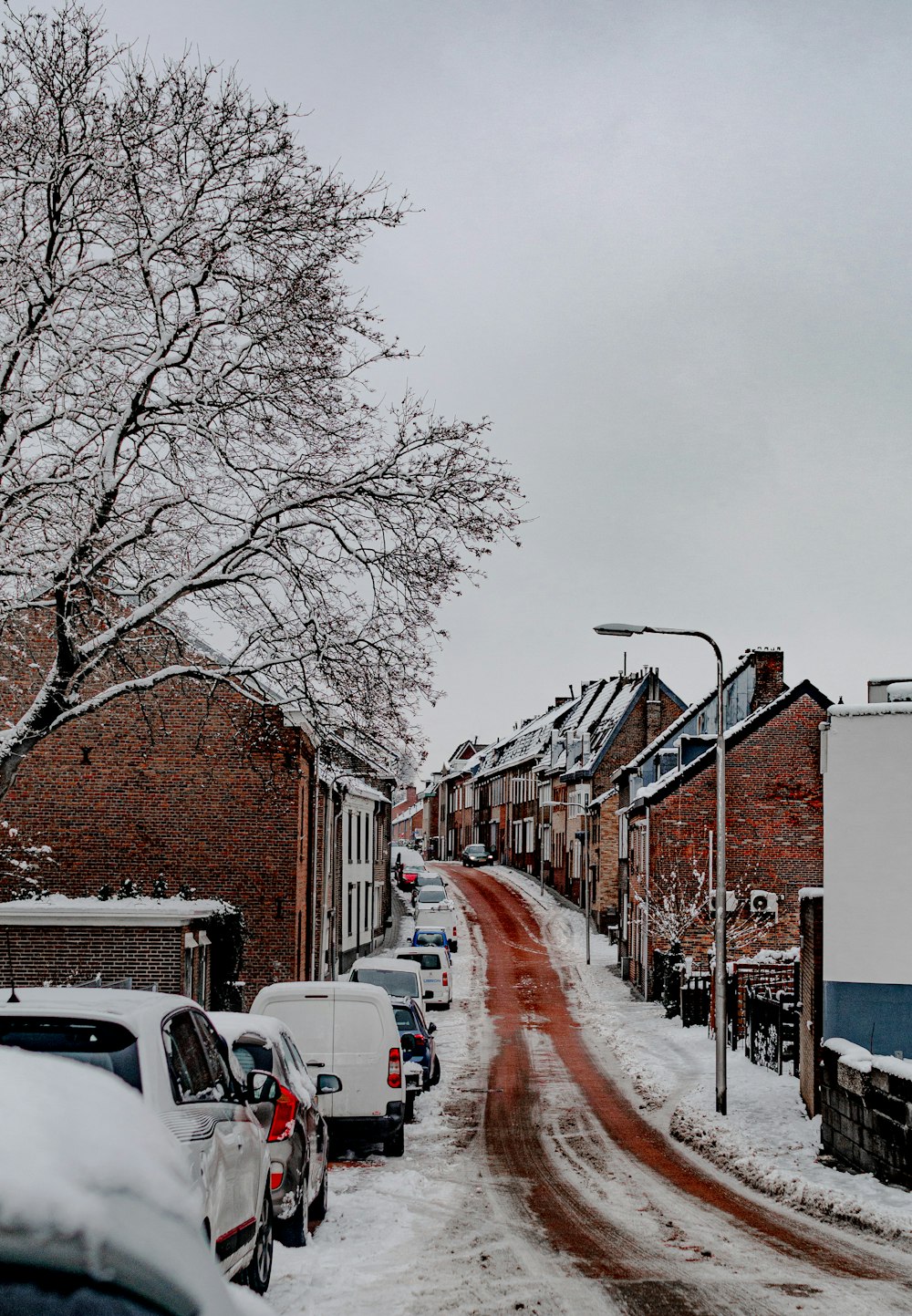 a snowy street with cars parked on the side of it