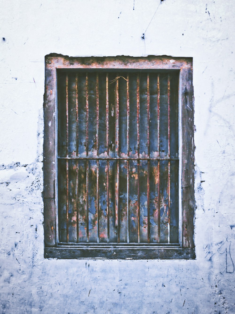 una ventana con rejas en una pared blanca