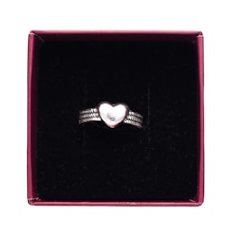 A silver ring with a heart-shaped centerpiece, placed inside a maroon box lined with a black, velvety material.