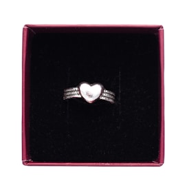 A silver ring with a heart-shaped centerpiece, placed inside a maroon box lined with a black, velvety material.
