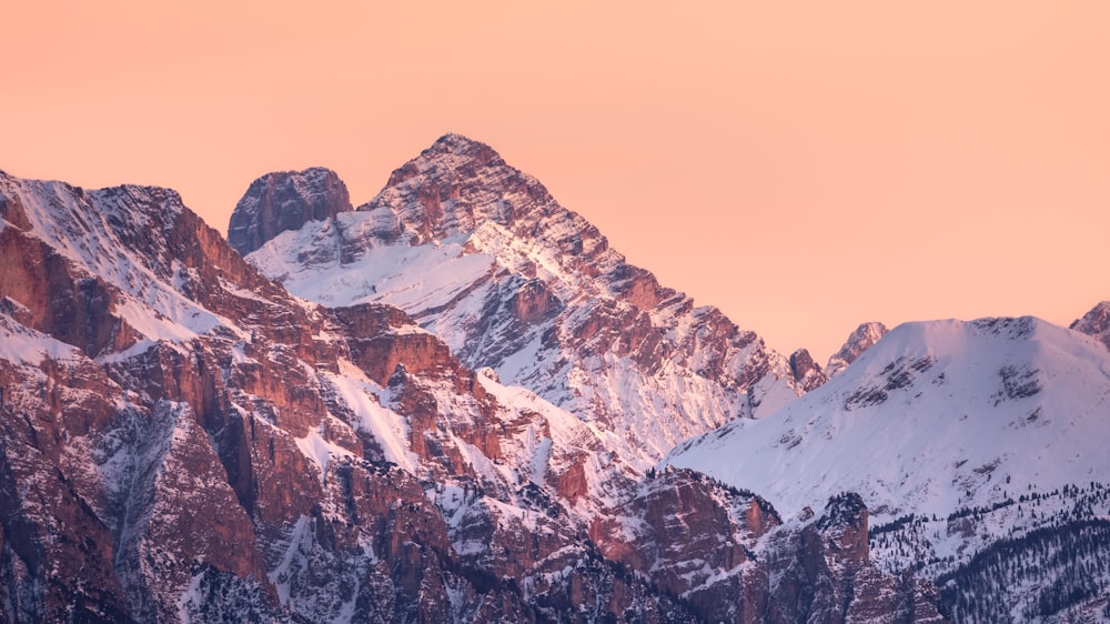 a mountain range covered in snow at sunset