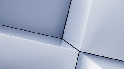 Minimalist close-up of a golden geometric shape softly illuminated on a creamy white background.