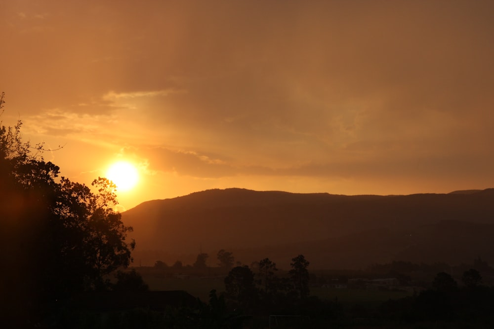 the sun is setting over a mountain range